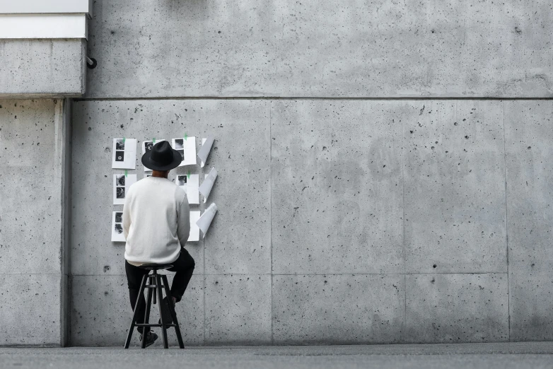 a woman in a hat riding a bike near a wall