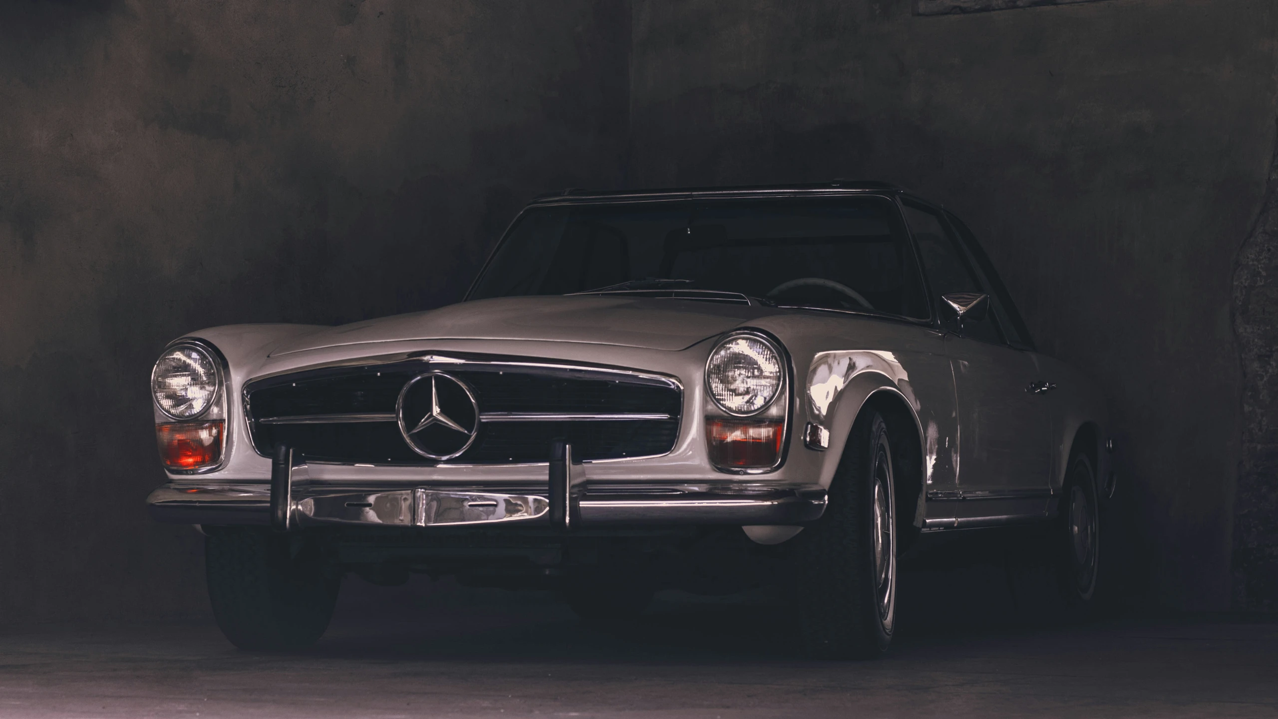 a mercedes benz sports car parked inside of a dark room