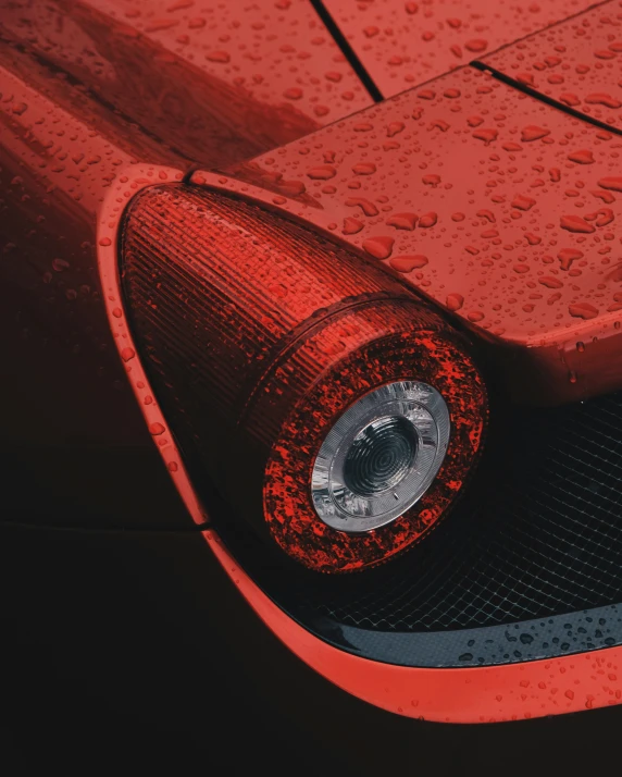 the front end of an orange car covered in water drops