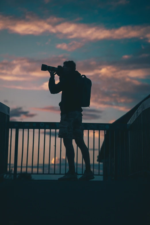 the man is standing on a bridge taking his po