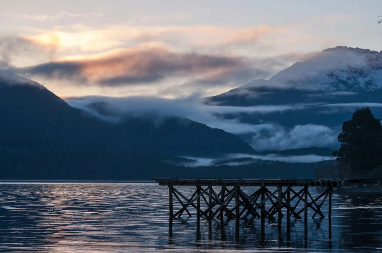 foggy mountain range beyond the ocean and dock on the water