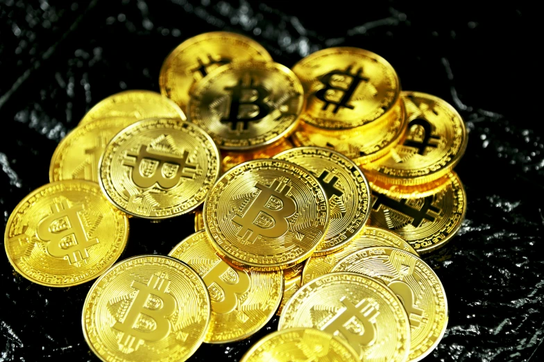 gold bitcoins are scattered around in this close up po