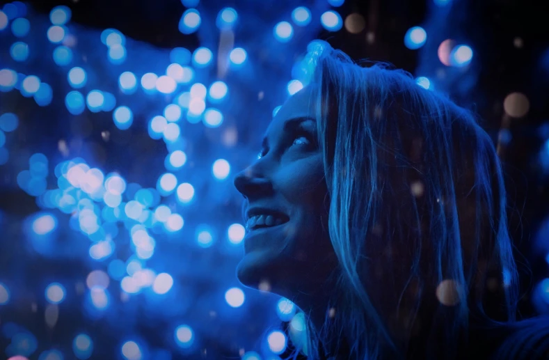 a woman smiles as she stands in front of a firework display