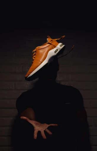 a person wearing orange shoes standing near a brick wall