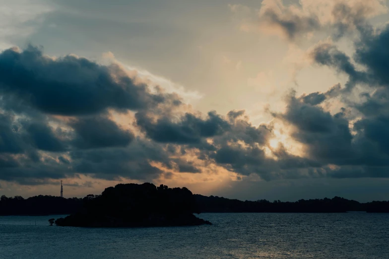 the clouds are above the island as sun goes down