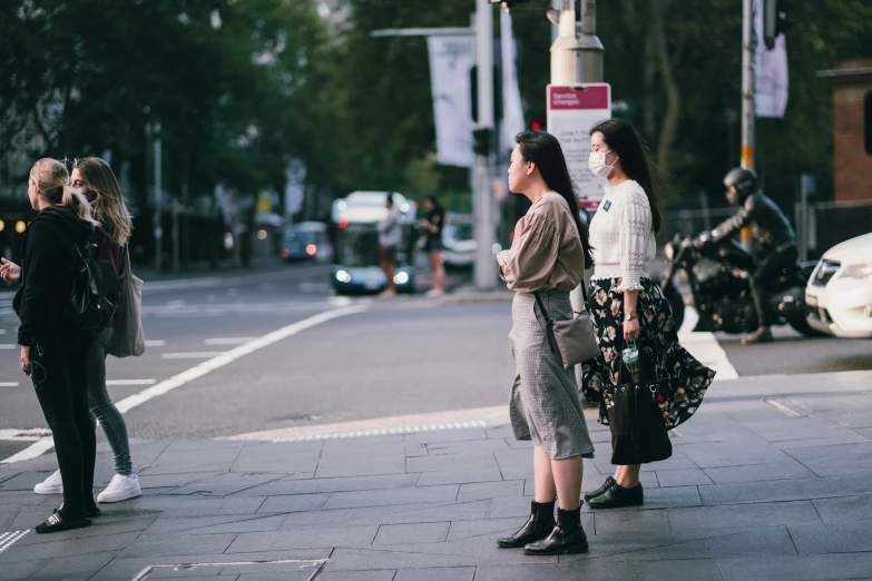 three women waiting at an intersection for the light to change