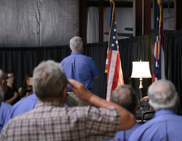 two men and a woman are speaking at a podium with the american flag on it