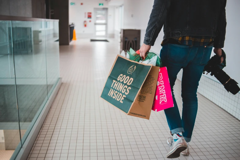 the man is carrying three bags in one hand