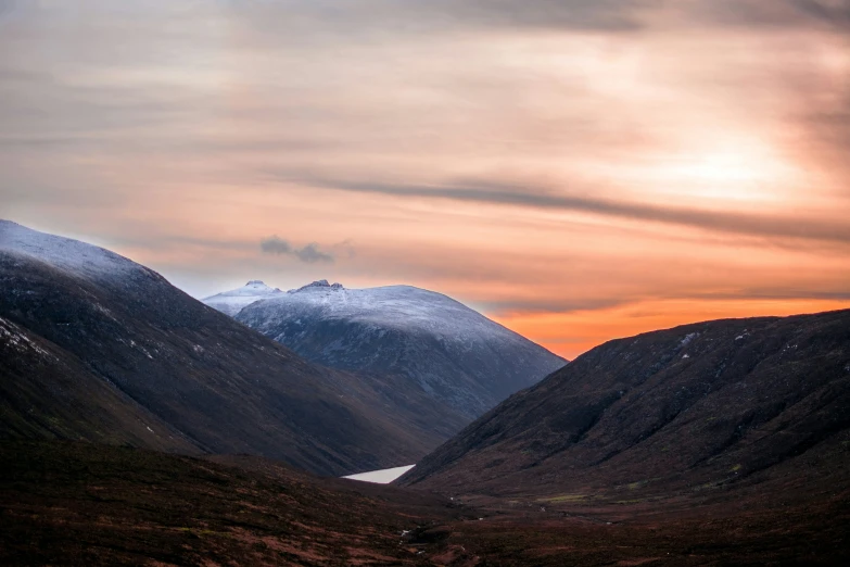 two mountains covered in snow at sunset