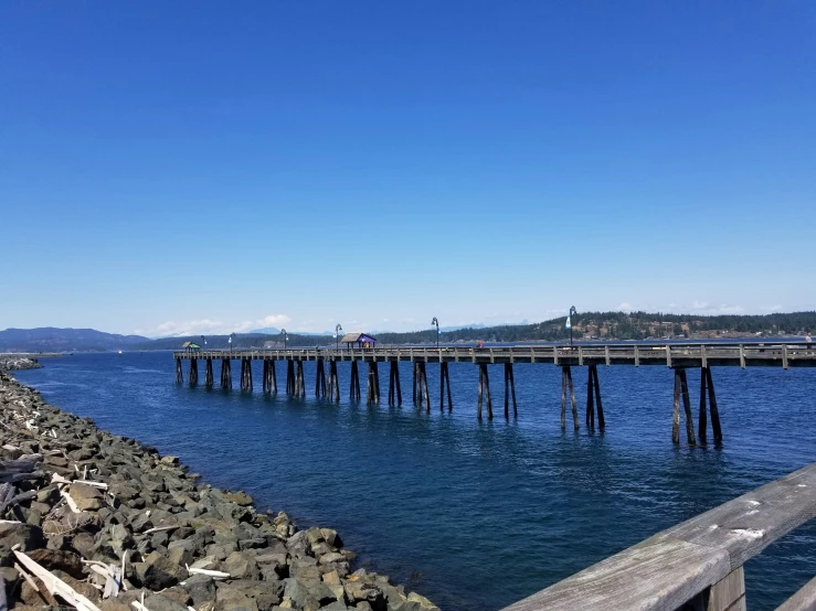 a long pier next to water with a sky background