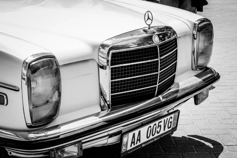 the front of an old mercedes parked on the street
