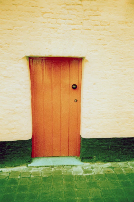 an orange wooden door sitting next to a white building