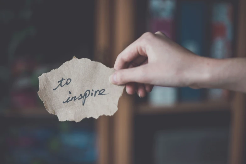 a person holding up a piece of paper that says, to inspire