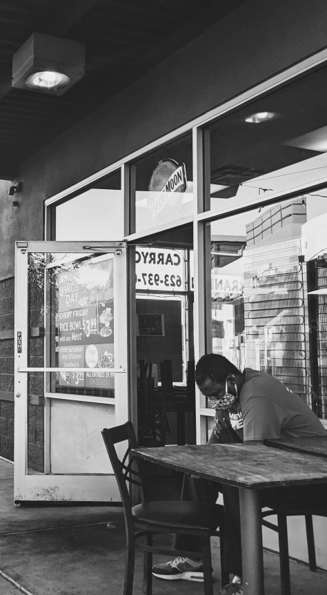 the person is asleep at a table outside the building