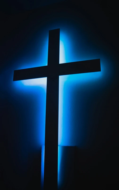 blue light is shining on a large cross