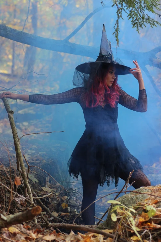 a woman dressed as a witch holding her broom and pointing