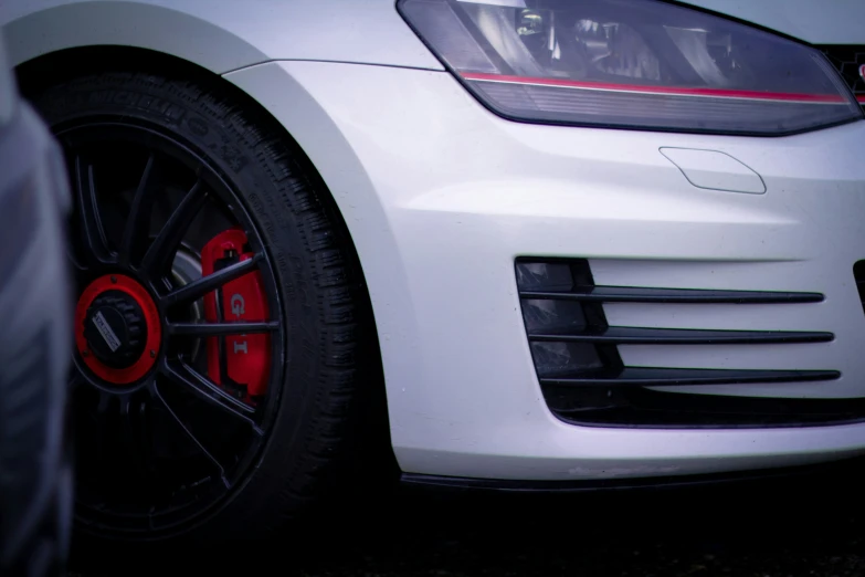 a white car with red rims parked in front of a building