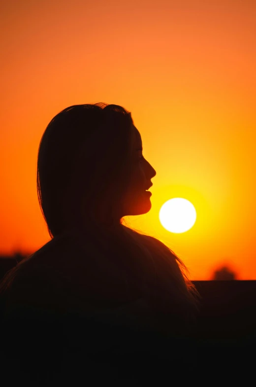 a person in silhouette with the sun setting behind them