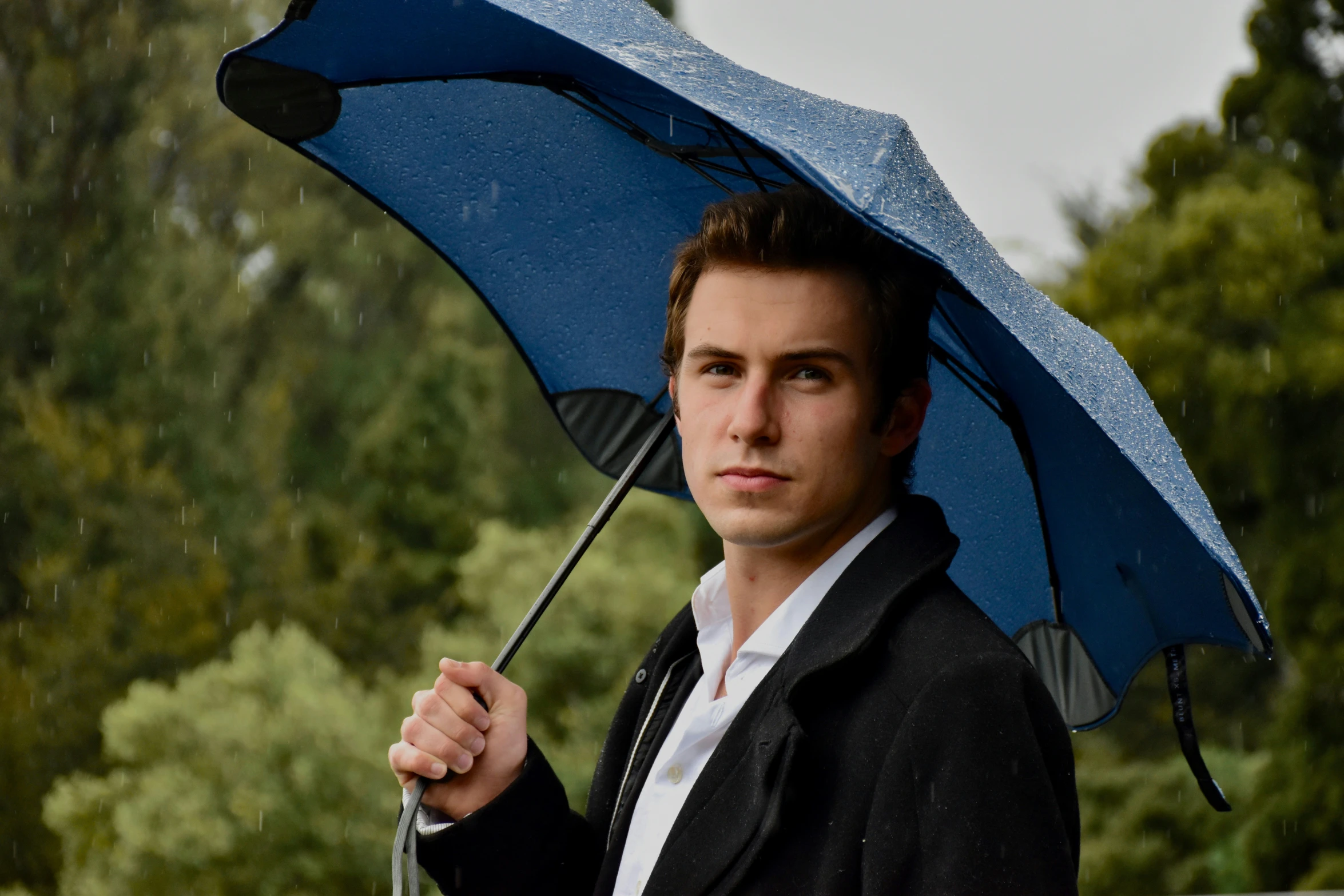 a man holding a blue umbrella in the rain