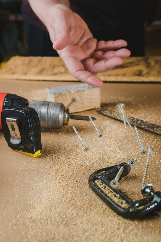 a man using a jik to attach nails to a wooden board