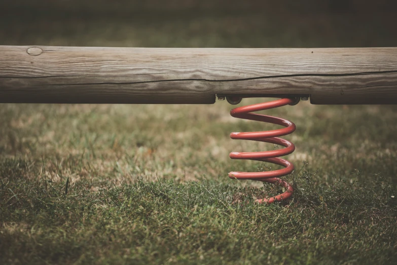 a wooden plank and springs attached to a metal ring in the grass