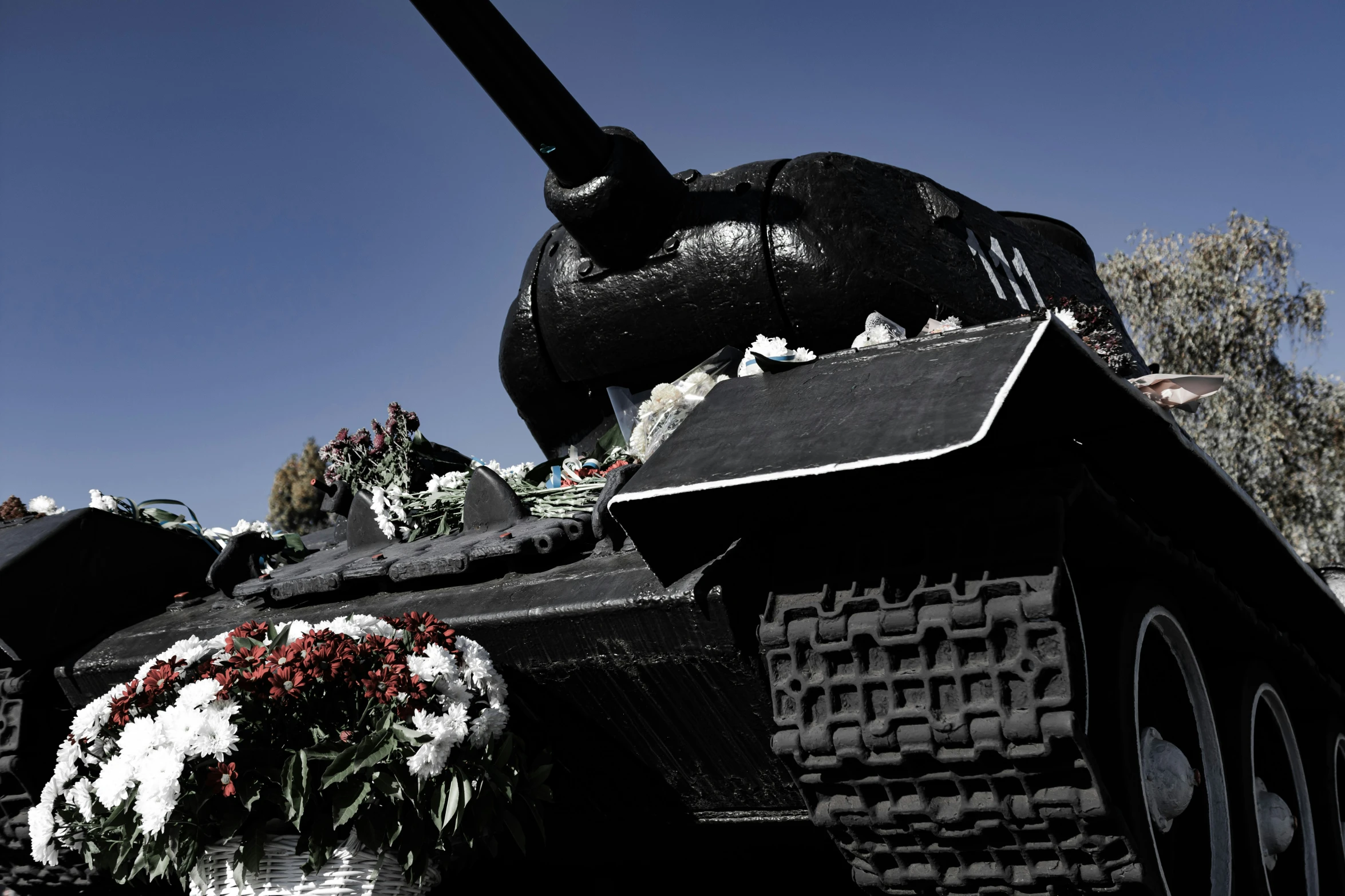 a tank sits with flowers and a building in the background