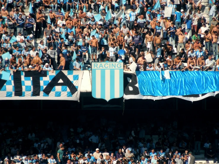 a large crowd watches as a man is standing on top of a soccer ball