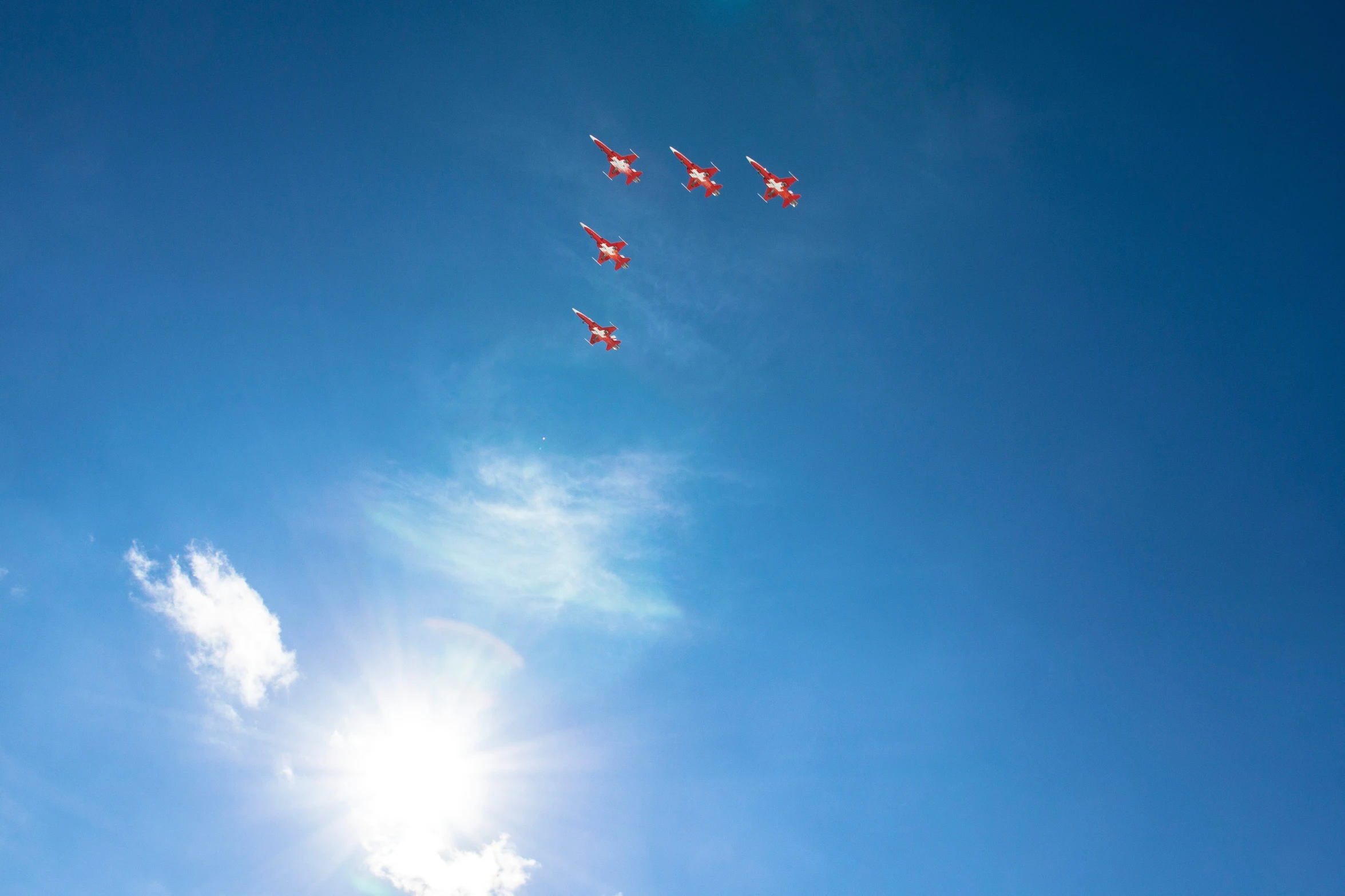 four red airplanes fly across the sky on a sunny day