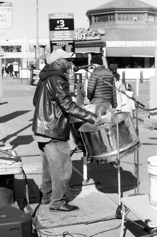 people standing on the side walk, one is holding a drum and another is holding soing