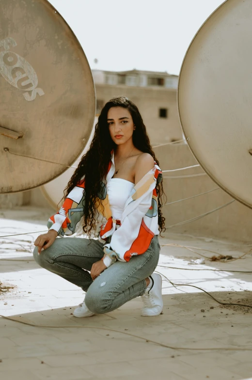 the woman is kneeling down next to four satellite dishes