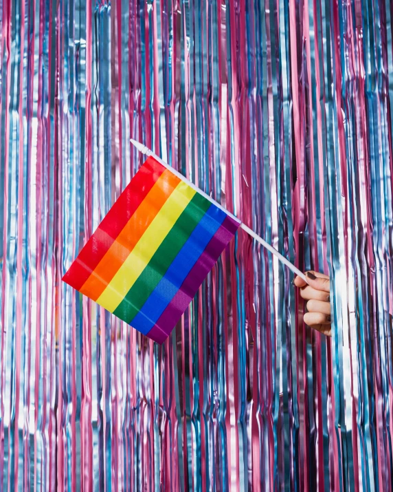 a person holding a kite over a rainbow colored wall