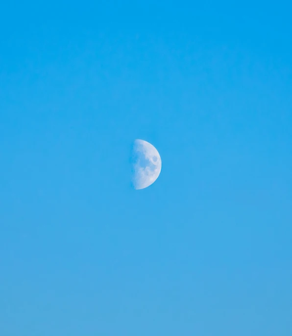 the sun is seen behind a distant half moon