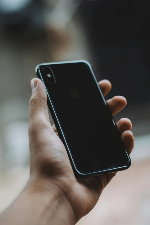 a hand holds a small black iphone with an empty screen