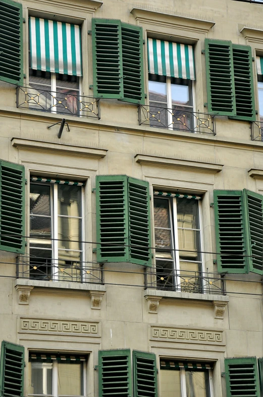 the windows and shutters on this building have green shades