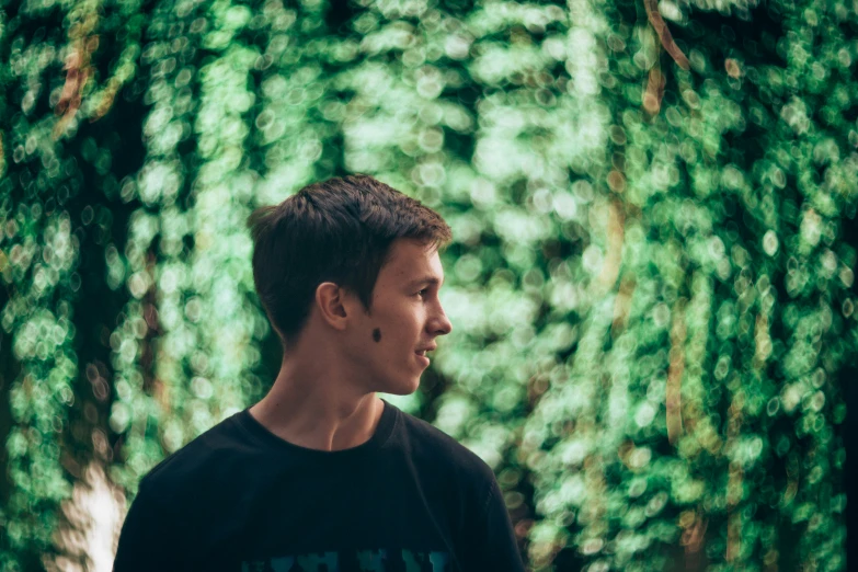 a man standing in front of a green leafy wall