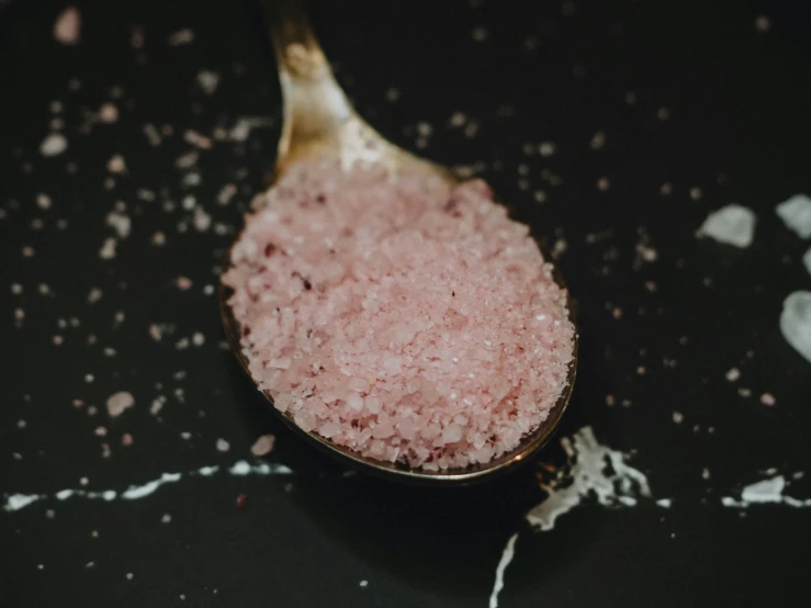 a spoon with sugar on a black table