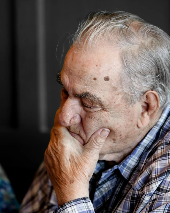 an older man sitting while holding his hand near his face