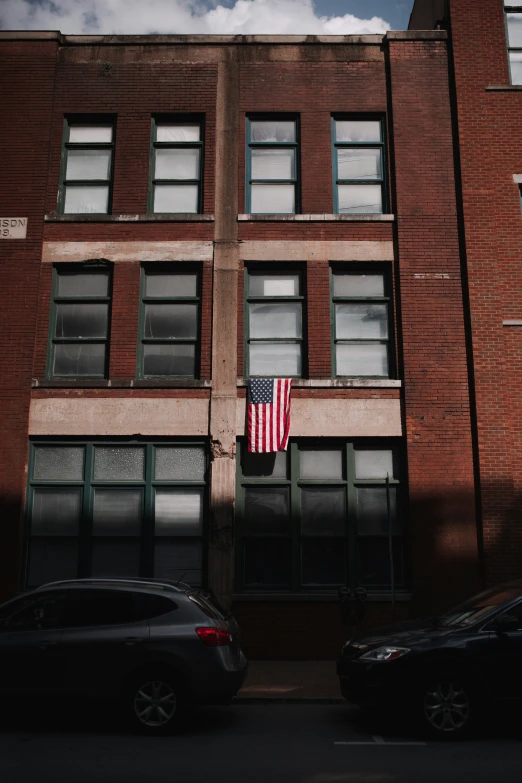 an american flag is in the window near some parked cars