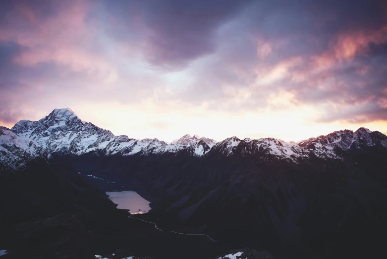 the mountains have been covered in snow as the sun sets