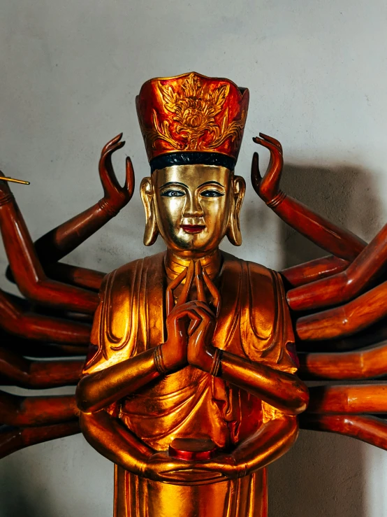 a gold statue with its arms outstretched and head open