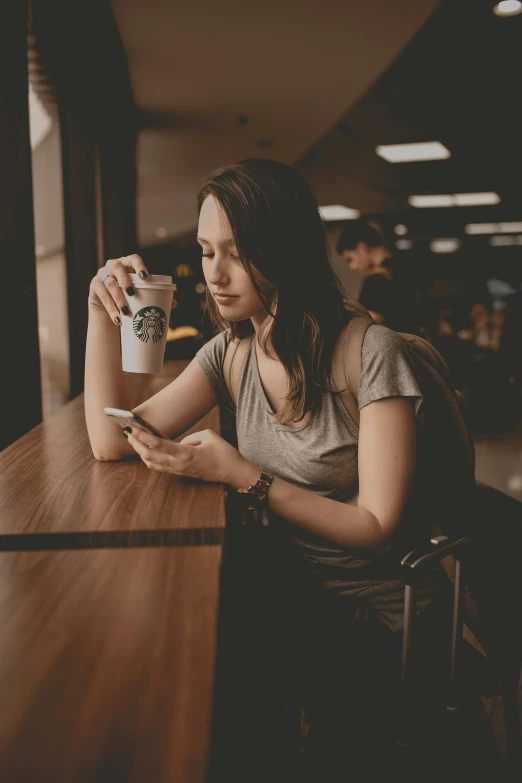 a young woman sitting at a table looking at her cellphone