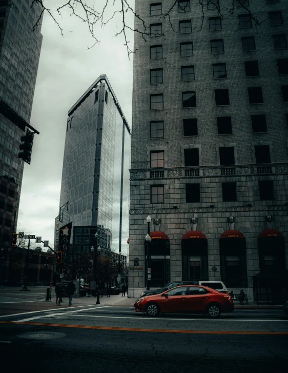 an orange car sits in front of two gray buildings