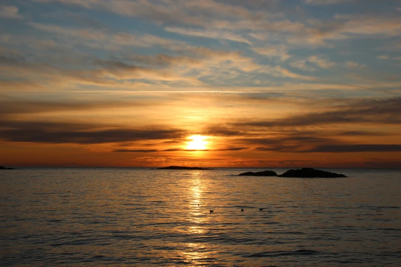 the sun is setting over the ocean with a boat in it