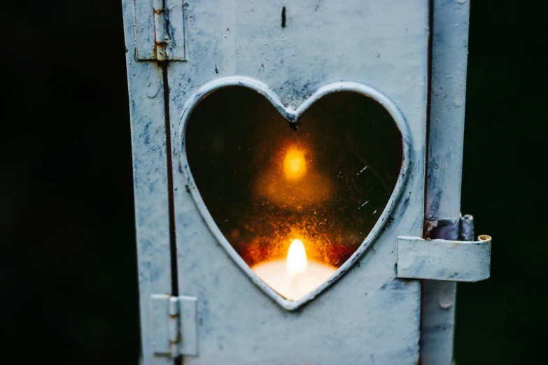 a candle in the shape of a heart on a steel door