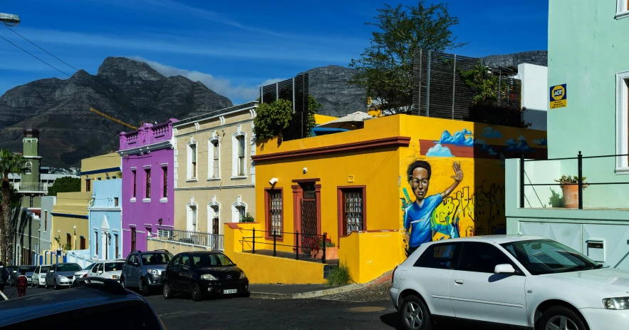 the street with many different colored houses is full of cars