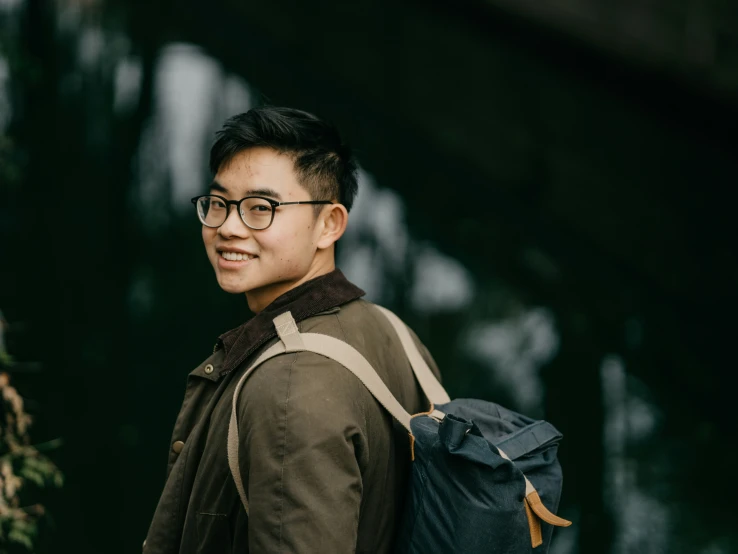 man in a brown coat wearing glasses and a backpack