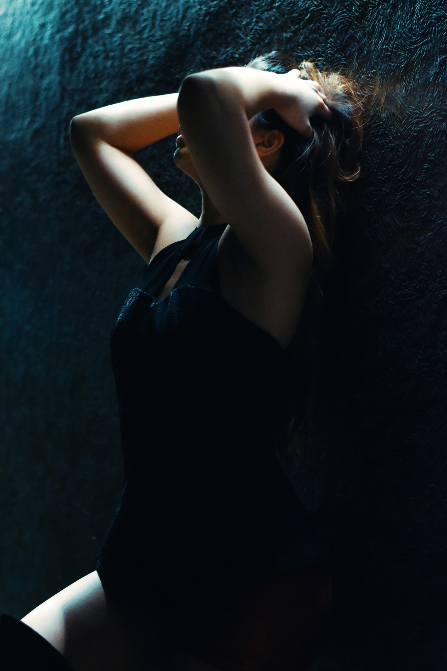 a woman leaning against a wall wearing black