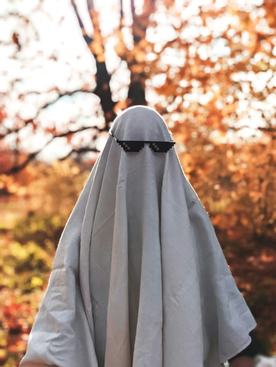 someone in a white and grey cloak with sunglasses on