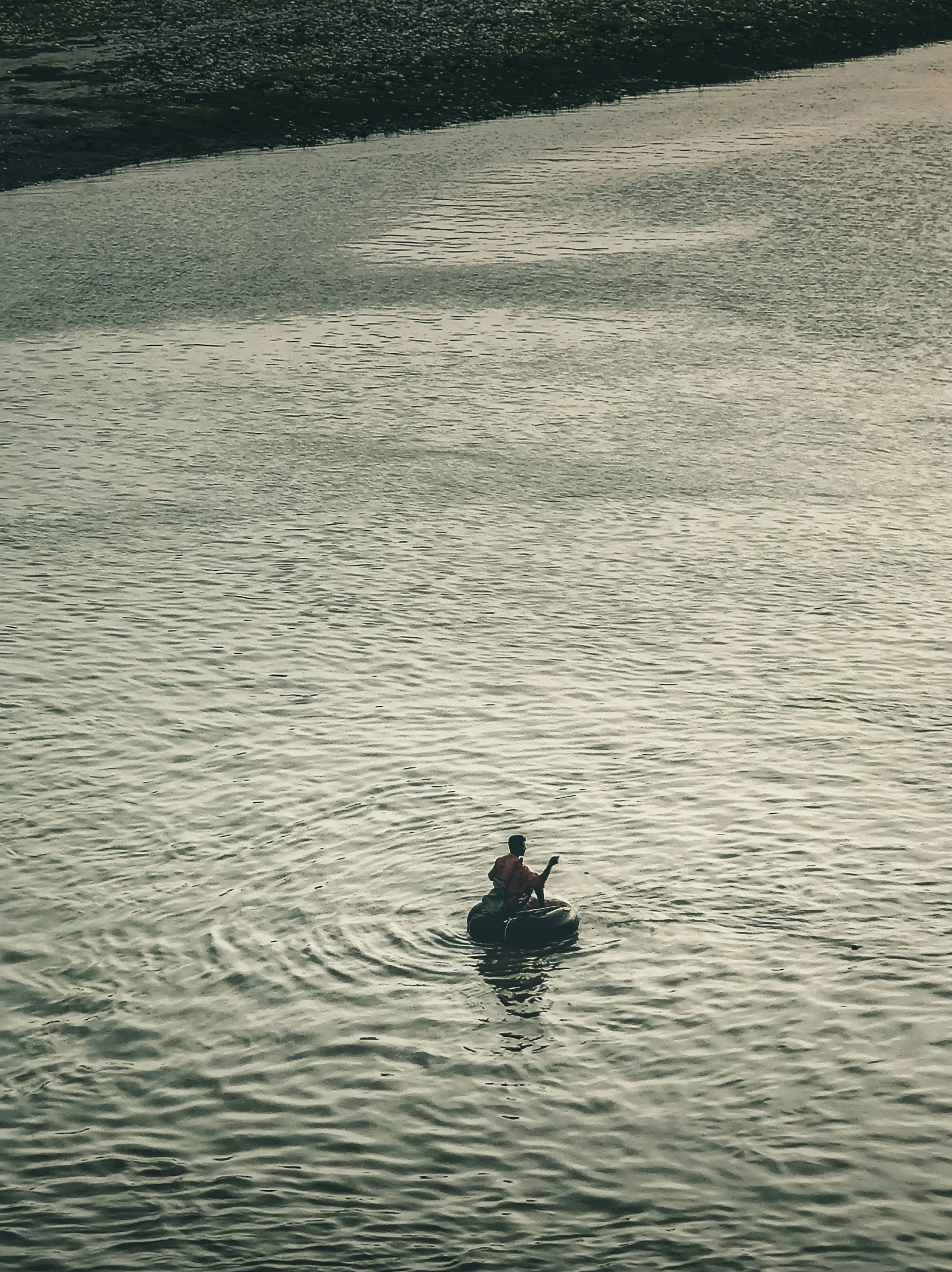 a lone person kayaks on the surface of water