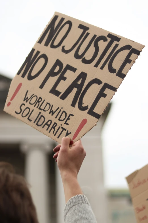 a man holds up a placard that reads no justice no peace